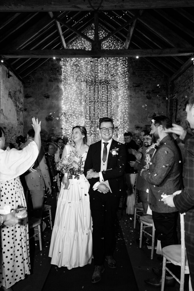 Bride and groom walking down aisle in black and white at The Normans York