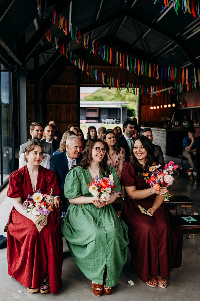 Bridesmaids smiling during ceremony at The Giraffe Shed