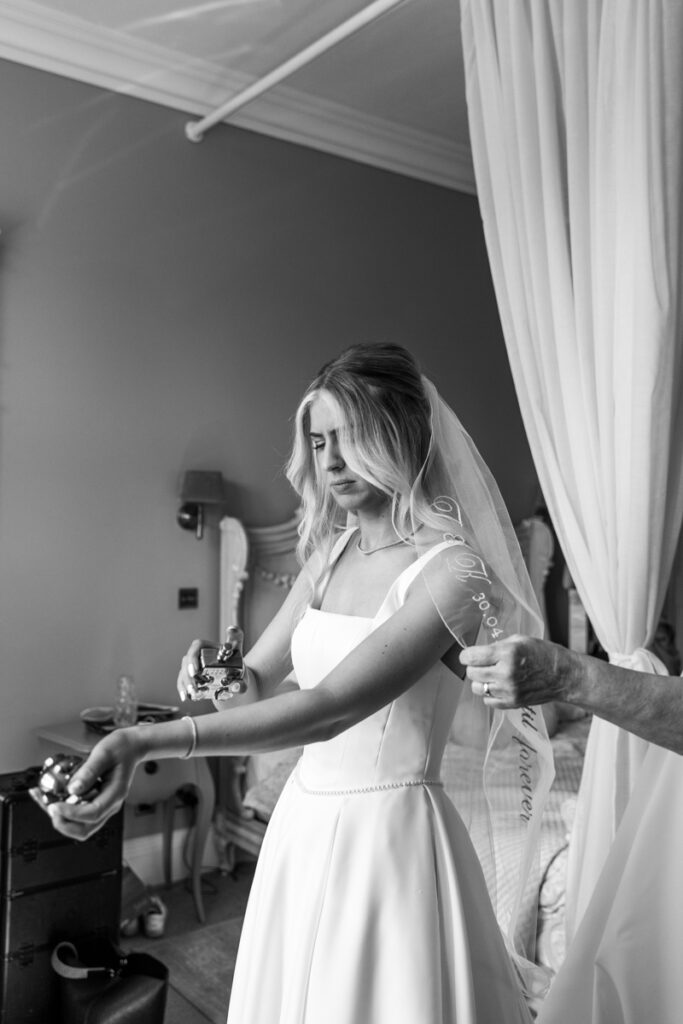 Bride putting perfume on at Thicket Priory