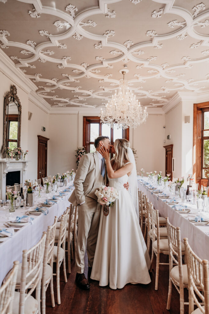 Bride and groom kissing in dining room at Thicket Priory