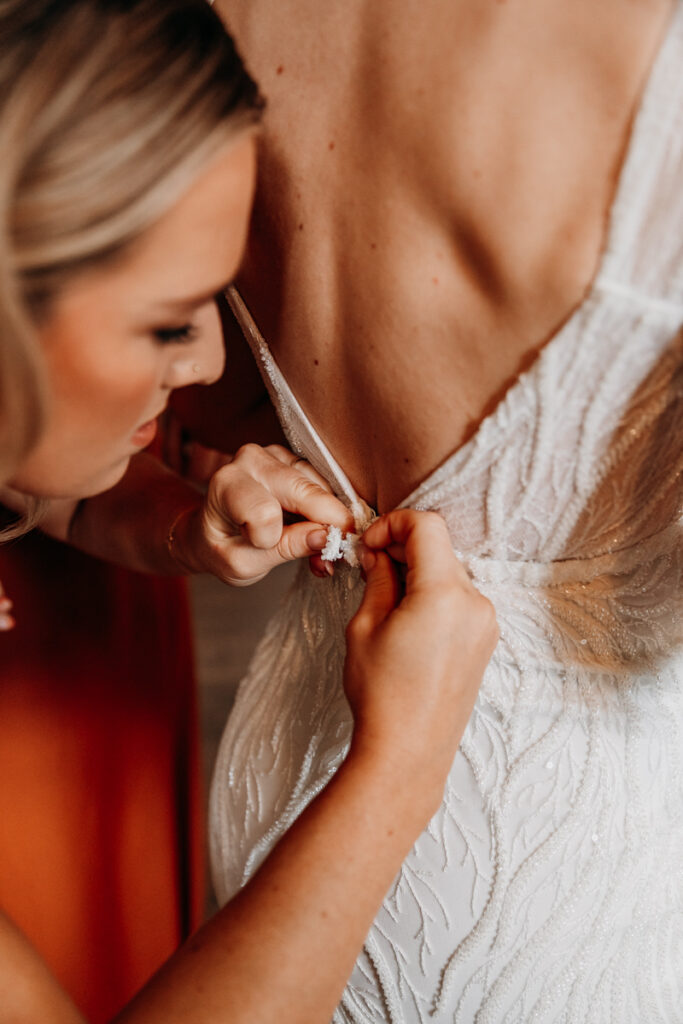 Bridesmaid doing up dress