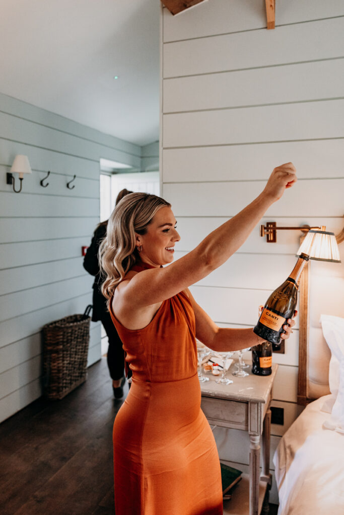 Bridesmaid opening champagne