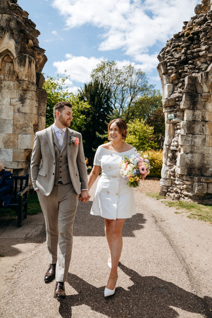 bride and Groom walking holding hands through York Museum Gardens