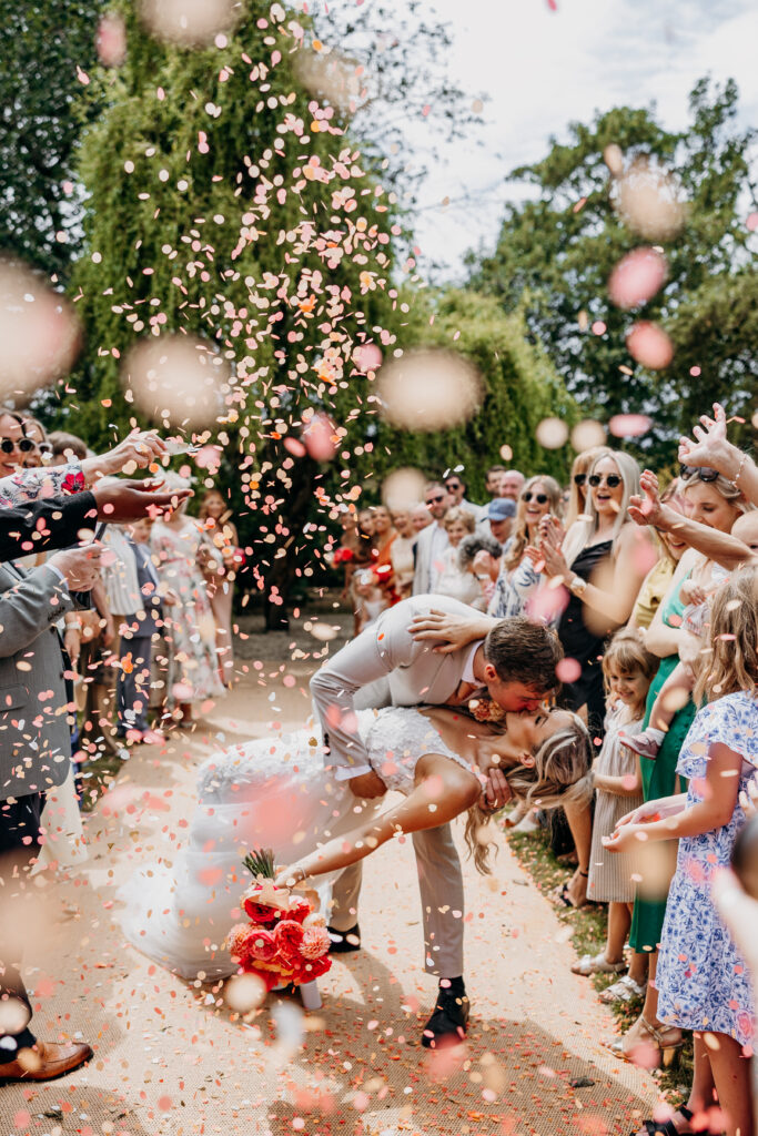 Bride and groom do dip kiss when walking through confetti throw in Leeds garden wedding