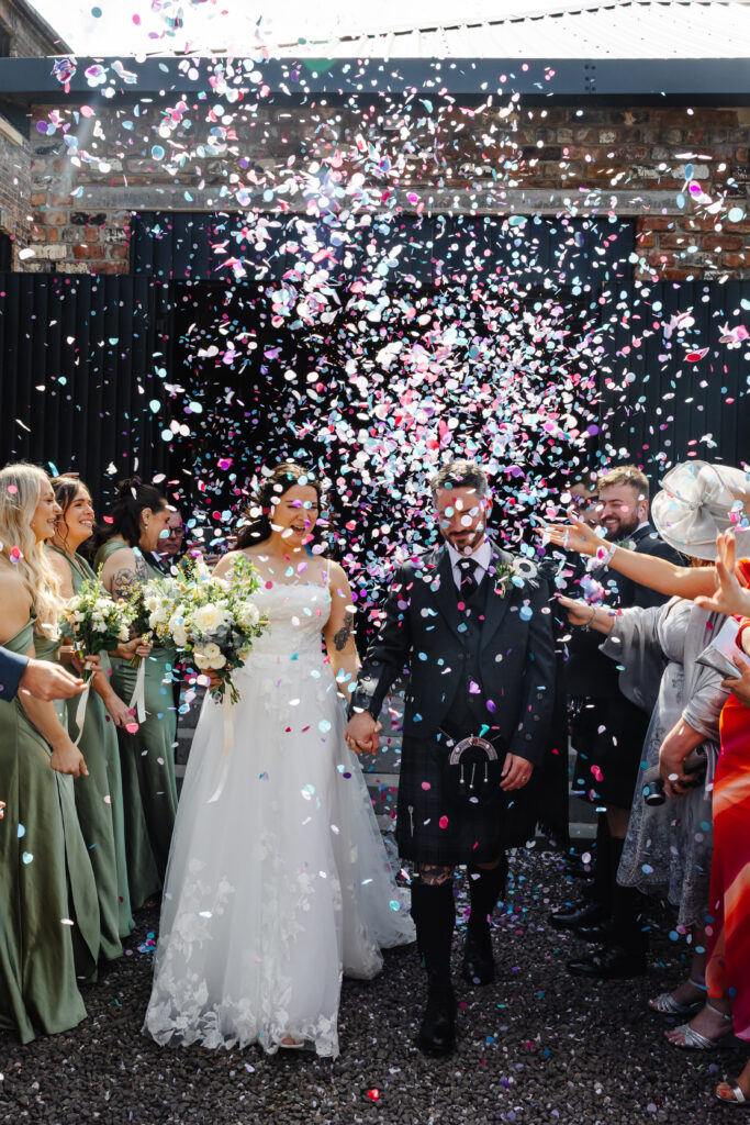 Bride and Groom walk through colourful confetti at The Engine Works Glasgow