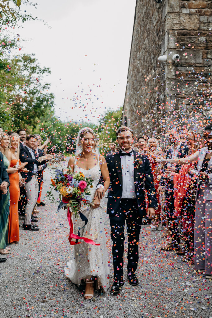 Bride and Groom walk through confetti at The Outbarn Clitheroe