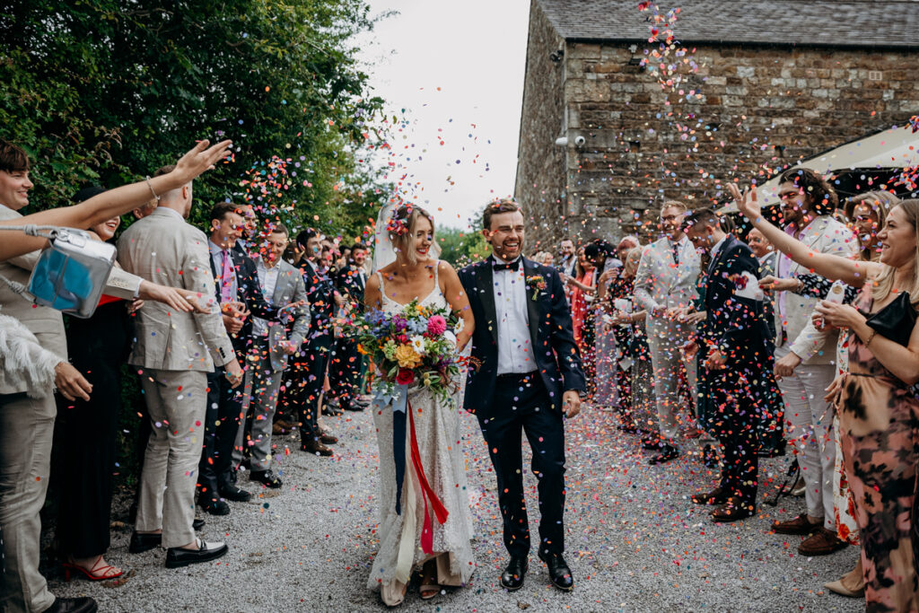 Bride and Groom walk through confetti at The Outbarn Clitheroe