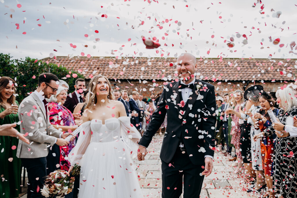 Bride and Groom walk through confetti at Thirsk Lodge Barn