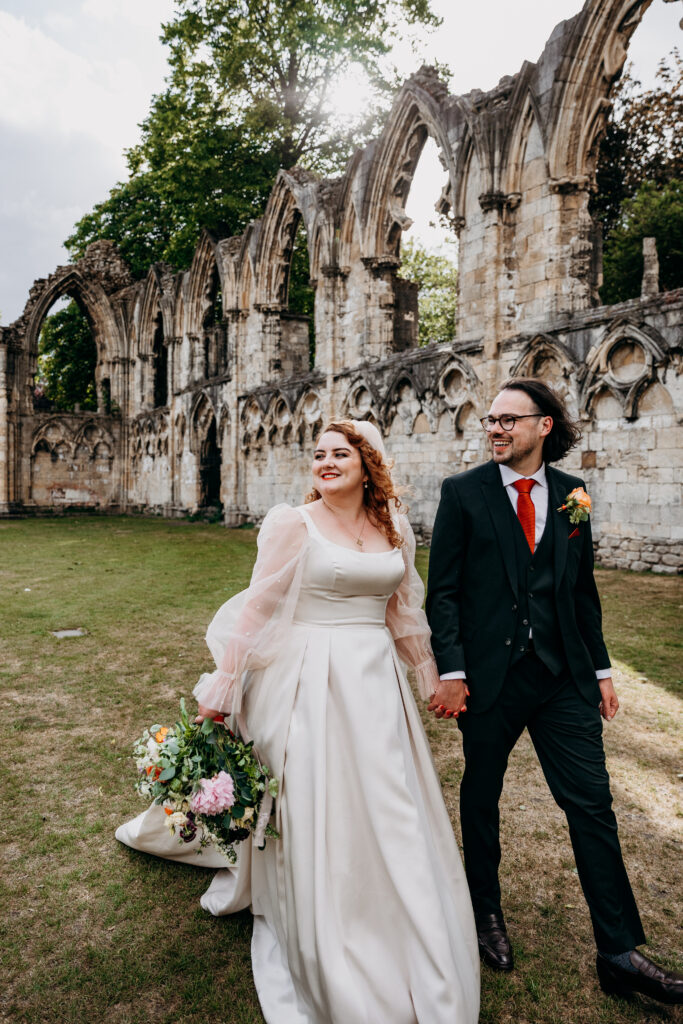 Bride and groom walking through York Museum Gardens