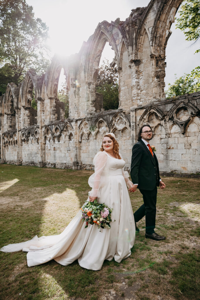 Bride and groom walking through York Museum Gardens