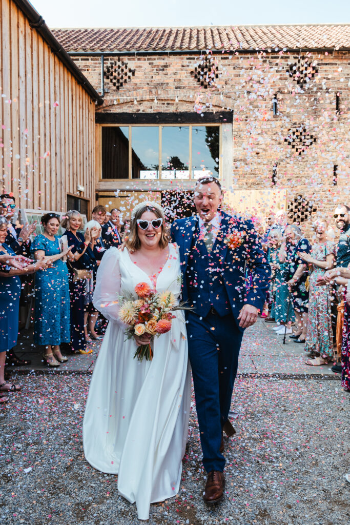 Bride and Groom walk through confetti line at Lodge Barn Weddings York