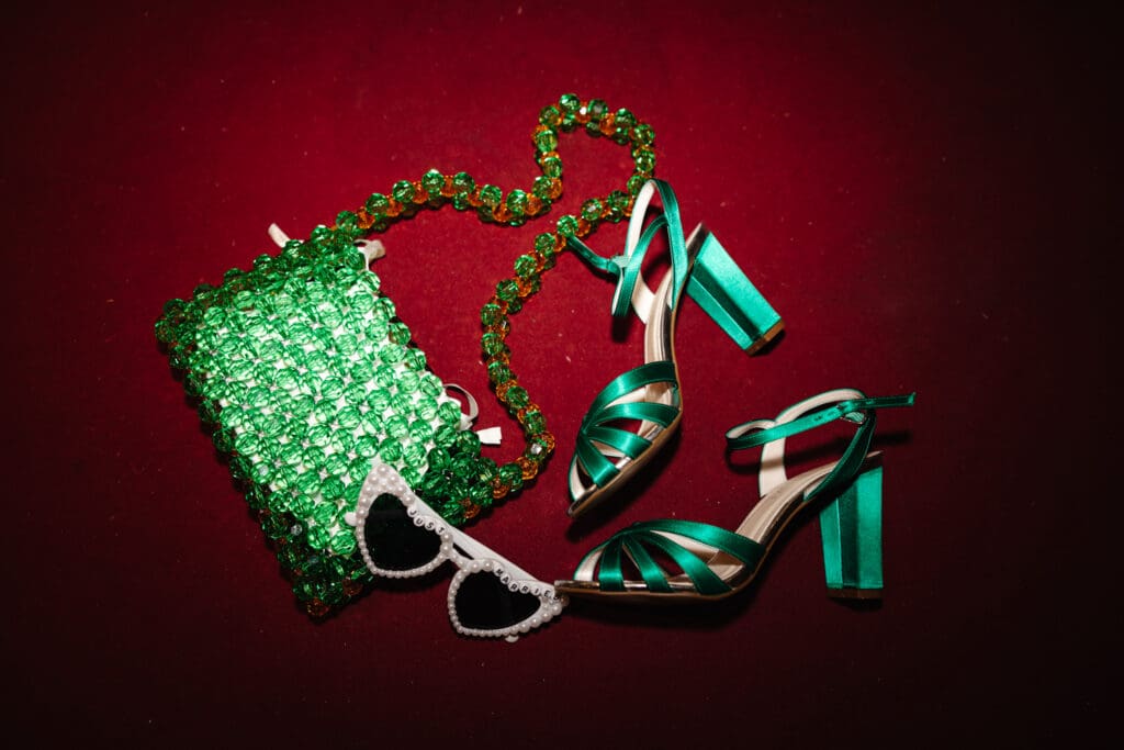 green wedding shoes and bag with sunglasses on red background